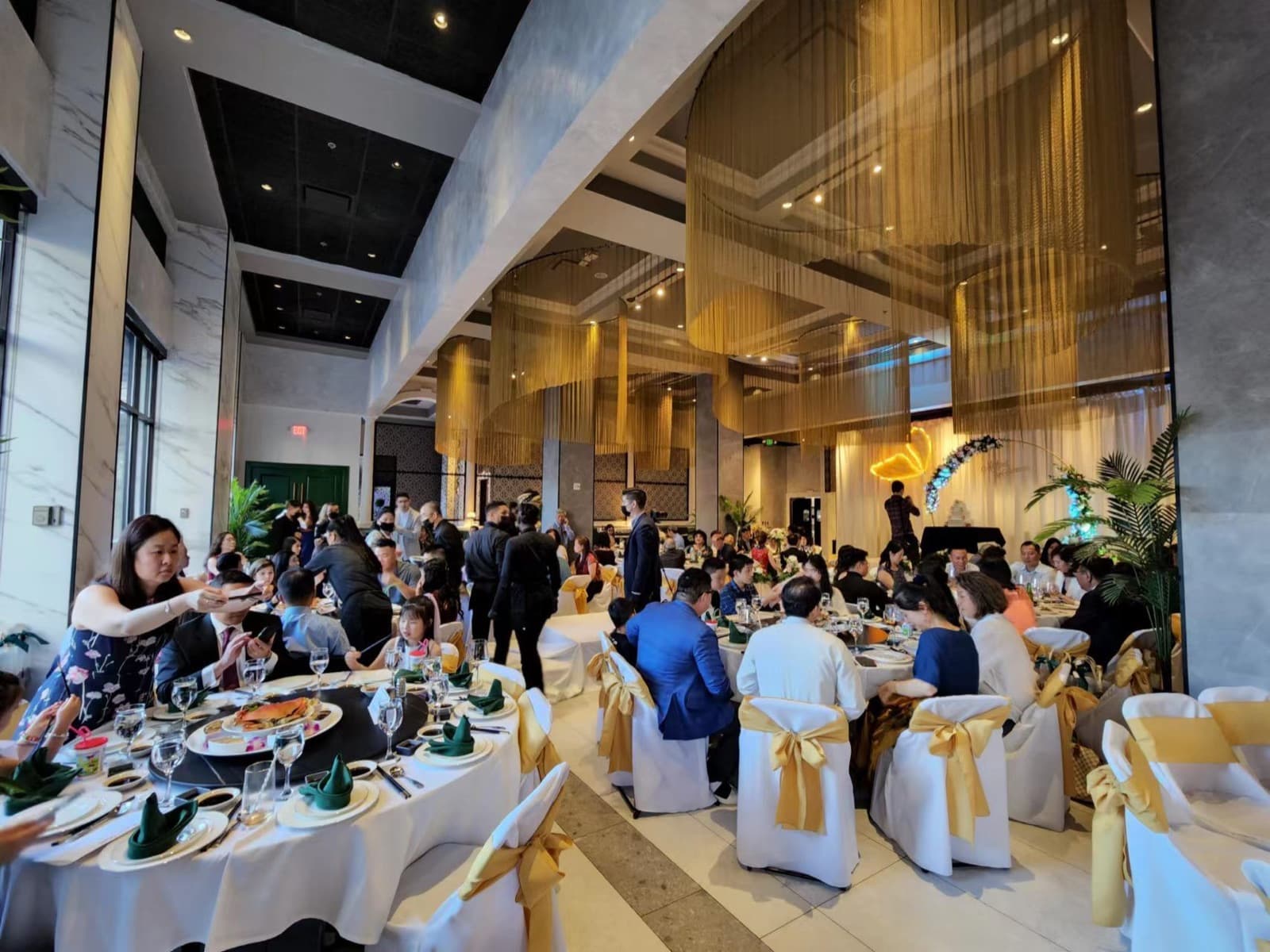 Guests seated at round banquet tables under gold drapes at an IVEA party